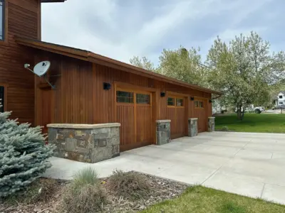 Wood-paneled building with multiple garage doors and a satellite dish on the left side of the wall.